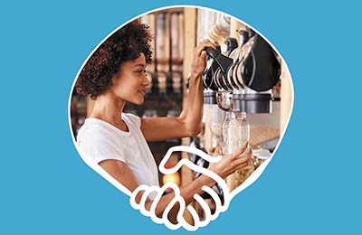 Photo of a person using a dispenser to refill a jar at a refill store